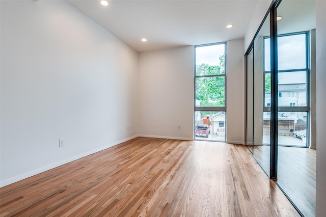empty room featuring expansive windows, recessed lighting, baseboards, and light wood-style flooring