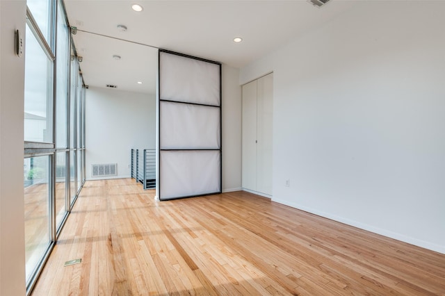 empty room with recessed lighting, baseboards, visible vents, and light wood finished floors