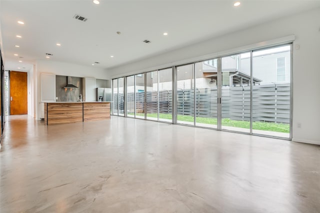 unfurnished living room featuring finished concrete flooring, plenty of natural light, and visible vents