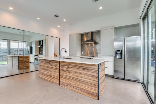 kitchen featuring finished concrete flooring, appliances with stainless steel finishes, modern cabinets, and wall chimney exhaust hood