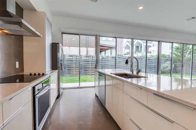 kitchen featuring visible vents, finished concrete flooring, wall chimney range hood, a sink, and appliances with stainless steel finishes