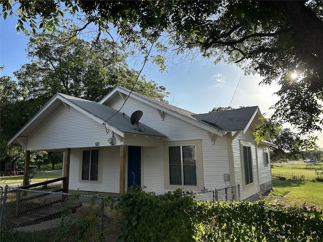 bungalow with roof with shingles, fence, and a front yard