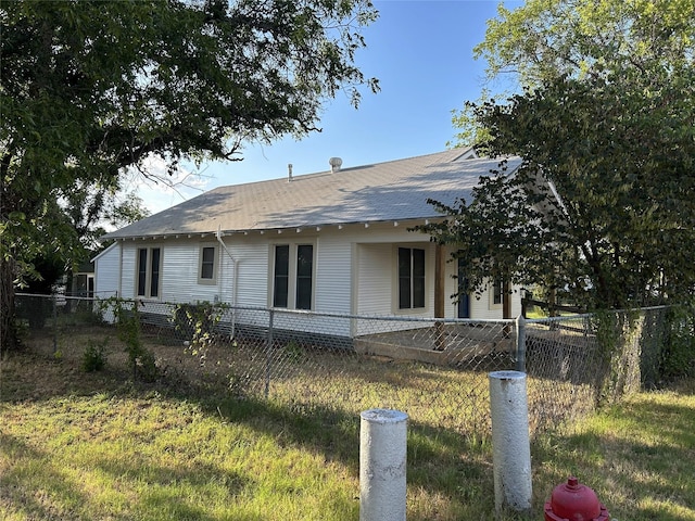 exterior space with roof with shingles and a fenced front yard