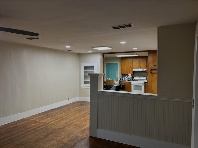 kitchen with visible vents, baseboards, gas range gas stove, under cabinet range hood, and brown cabinets