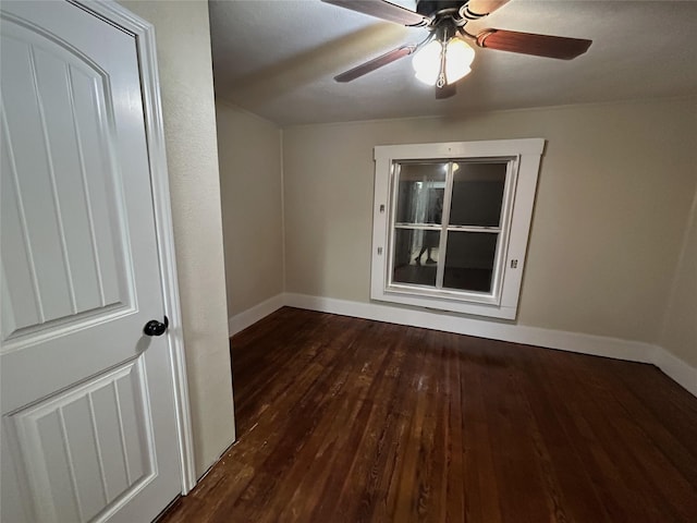 empty room featuring baseboards, ceiling fan, and dark wood-type flooring