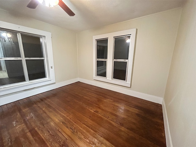 empty room featuring baseboards, dark wood finished floors, and ceiling fan