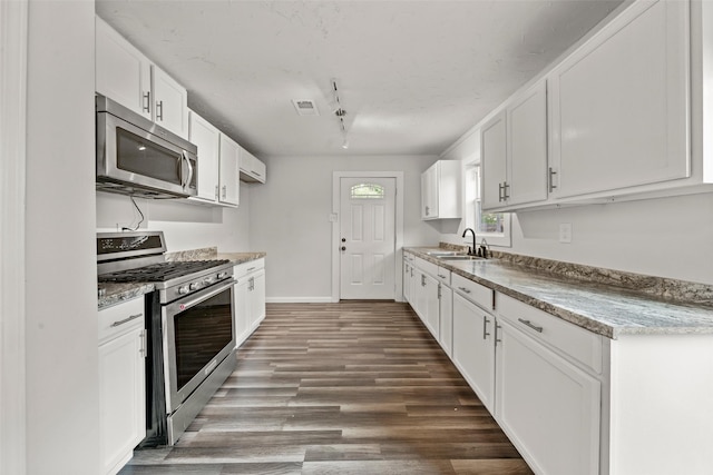 2301 Connor Ave, Waco, TX 76706 - kitchen with white cabinets, appliances with stainless steel finishes, a sink, wood finished floors, and visible vents
