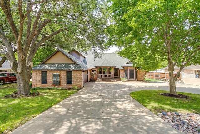 7116 Westover Dr, Granbury, TX 76049 - view of front of home featuring brick siding, curved driveway, a shingled roof, and a front lawn