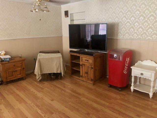 bedroom with a wainscoted wall, a ceiling fan, wallpapered walls, and light wood-style flooring