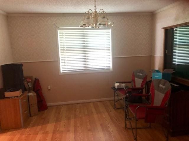 sitting room featuring crown molding, a notable chandelier, a textured ceiling, wallpapered walls, and wood finished floors