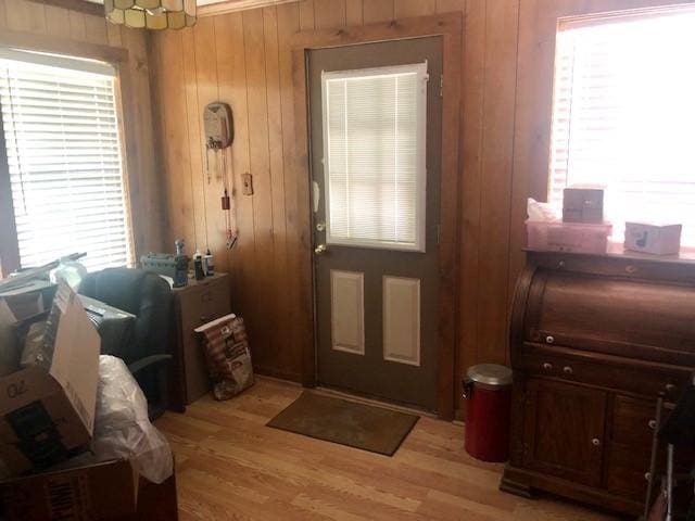doorway to outside featuring light wood-type flooring and wooden walls
