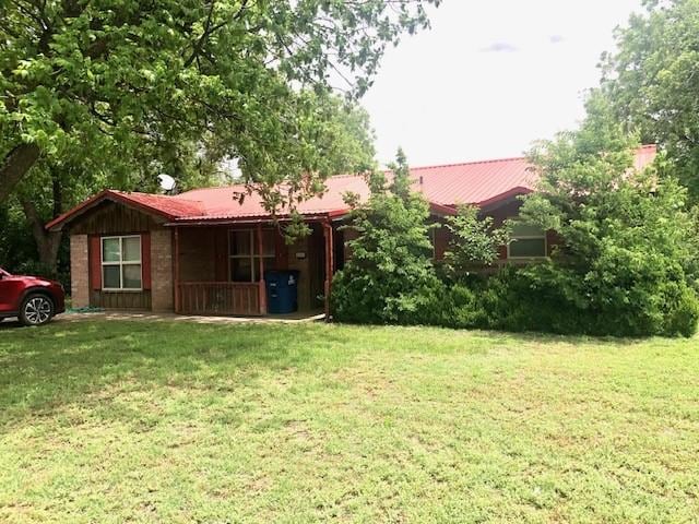 rear view of property with a yard and metal roof