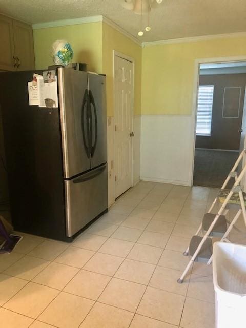 kitchen with crown molding, light tile patterned floors, and freestanding refrigerator