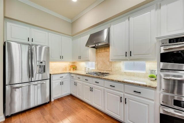 kitchen featuring crown molding, wall chimney exhaust hood, appliances with stainless steel finishes, and white cabinetry