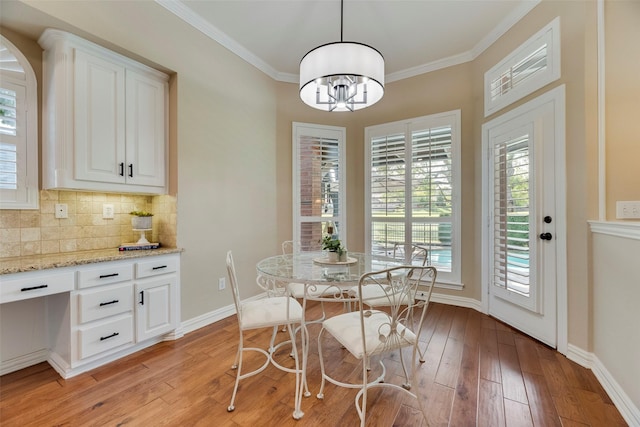 dining room with crown molding, baseboards, a chandelier, and light wood-style floors