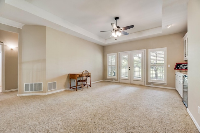 sitting room featuring visible vents, a ceiling fan, a raised ceiling, and light carpet