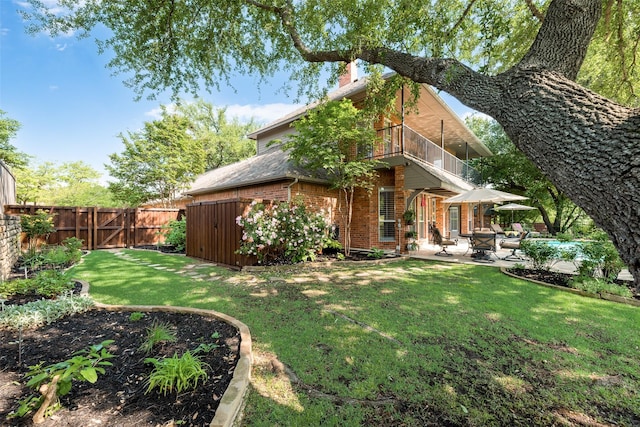 exterior space with brick siding, a fenced backyard, a chimney, a patio area, and a balcony