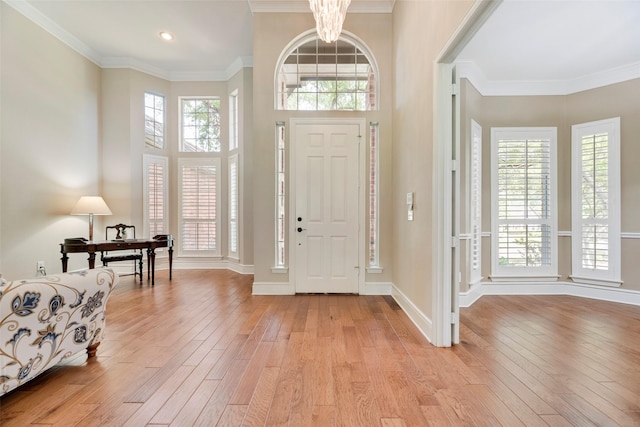 entrance foyer featuring an inviting chandelier, baseboards, ornamental molding, and light wood finished floors
