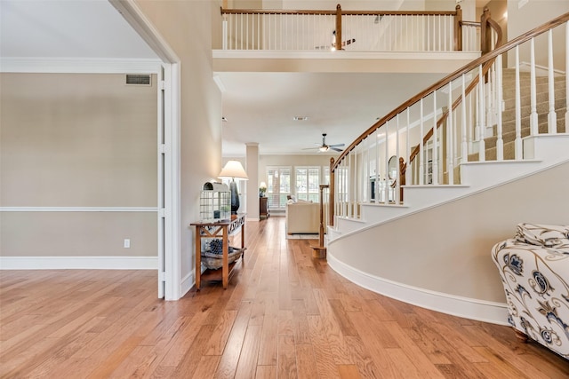 foyer entrance with ceiling fan, visible vents, crown molding, stairway, and hardwood / wood-style floors