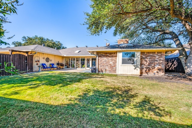 back of property with brick siding, fence, a yard, and a patio