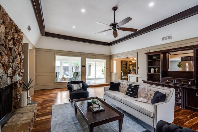 living area featuring ceiling fan, dark wood-style flooring, visible vents, a high ceiling, and a decorative wall