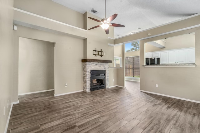unfurnished living room with visible vents, dark wood-style flooring, a fireplace, baseboards, and ceiling fan