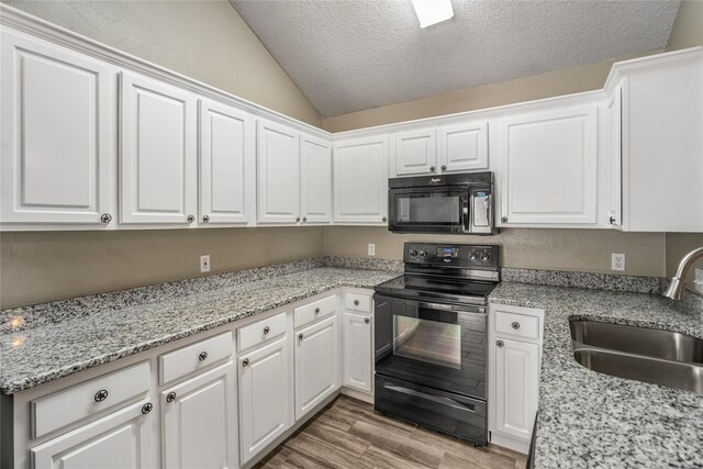 kitchen featuring a sink, white cabinetry, lofted ceiling, and black appliances