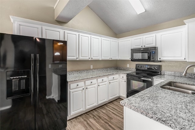 kitchen featuring a sink, white cabinets, vaulted ceiling, and black appliances