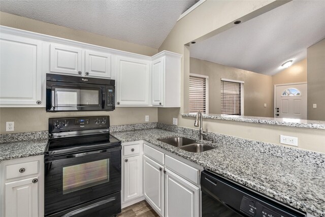 kitchen featuring wood finished floors, a sink, white cabinets, black appliances, and lofted ceiling