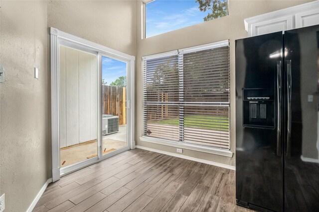 unfurnished dining area featuring baseboards, a textured wall, and wood finished floors