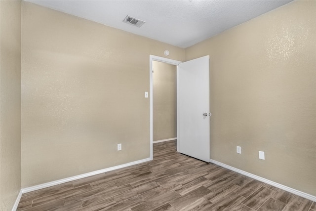 empty room featuring baseboards, wood finished floors, and visible vents
