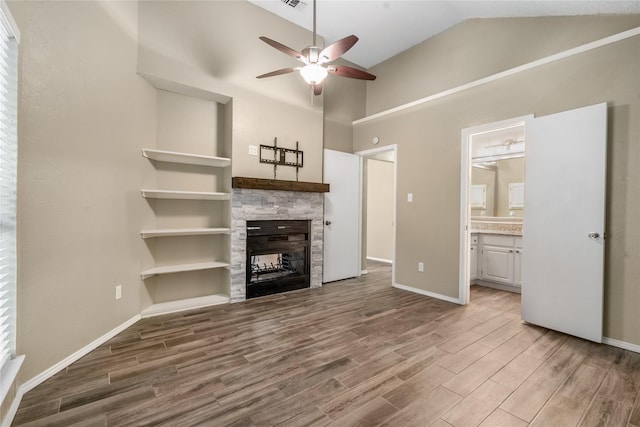 unfurnished living room with a ceiling fan, high vaulted ceiling, wood finished floors, and a fireplace