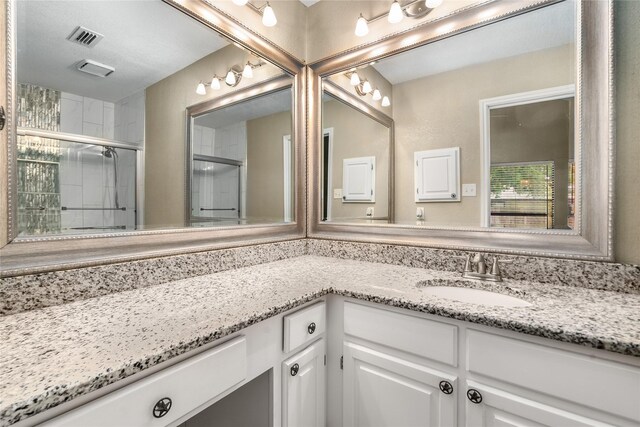 bathroom featuring vanity, visible vents, and a tile shower