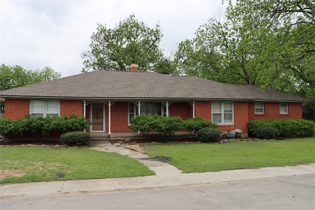 ranch-style house featuring a chimney, brick siding, and a front yard