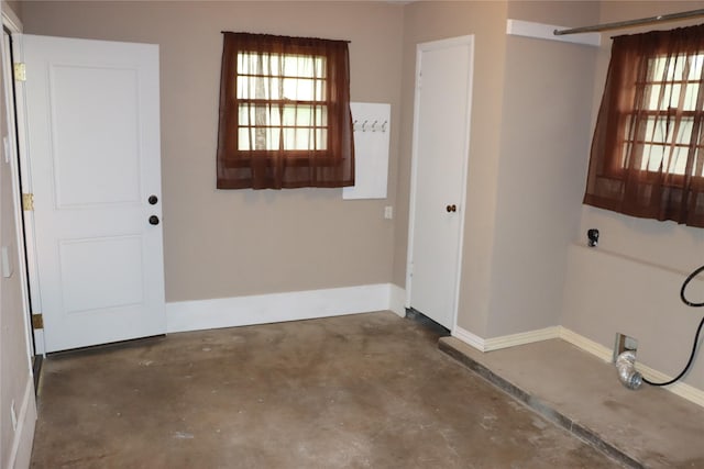 interior space with baseboards, a healthy amount of sunlight, and unfinished concrete flooring