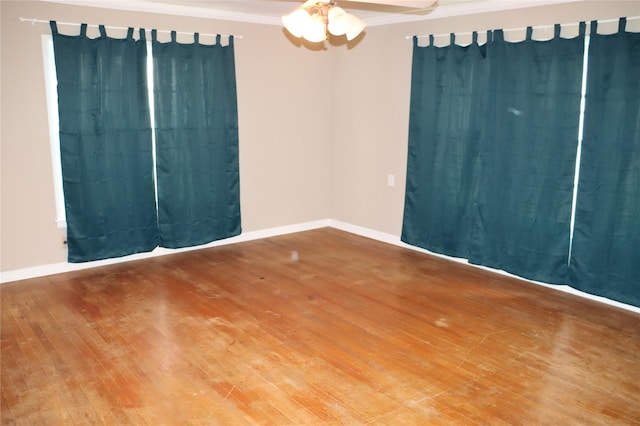 spare room featuring crown molding, baseboards, ceiling fan, and wood finished floors
