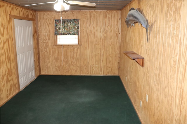 unfurnished room featuring carpet flooring, ceiling fan, and wooden walls
