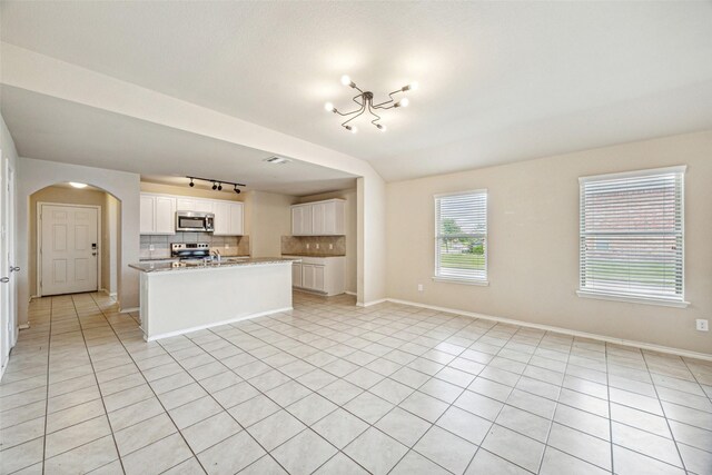 994 Decker Dr, Fate, TX 75189 - unfurnished living room with rail lighting, arched walkways, light tile patterned floors, and baseboards