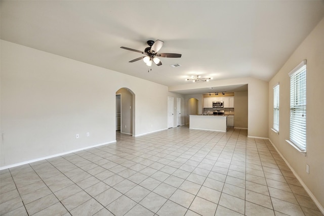 994 Decker Dr, Fate, TX 75189 - unfurnished living room featuring arched walkways, a ceiling fan, light tile patterned flooring, and baseboards