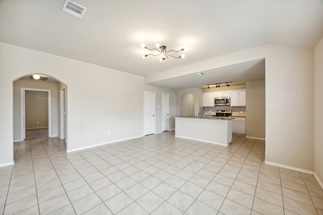 994 Decker Dr, Fate, TX 75189 - unfurnished living room featuring arched walkways, baseboards, a sink, and rail lighting