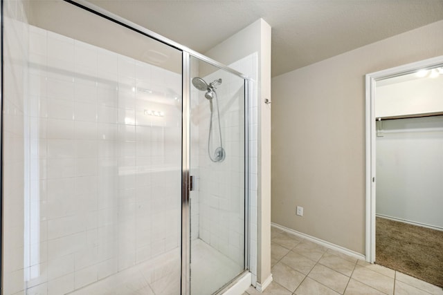994 Decker Dr, Fate, TX 75189 - bathroom with a stall shower, tile patterned floors, a walk in closet, and baseboards