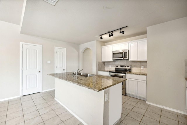 994 Decker Dr, Fate, TX 75189 - kitchen with appliances with stainless steel finishes, a sink, light tile patterned flooring, arched walkways, and a kitchen island with sink