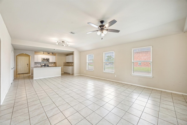 994 Decker Dr, Fate, TX 75189 - unfurnished living room featuring a ceiling fan, light tile patterned floors, plenty of natural light, and arched walkways