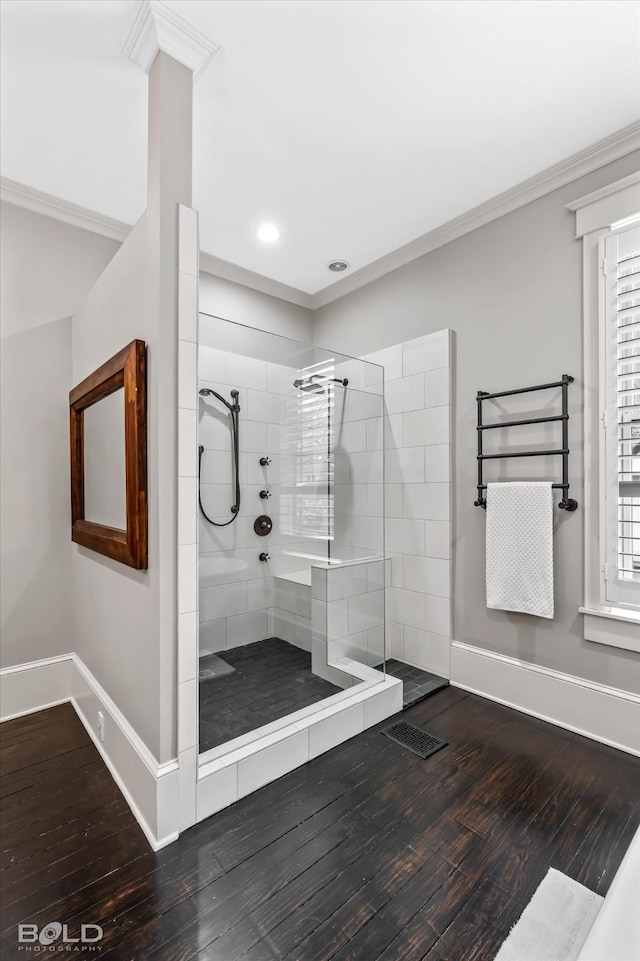 bathroom with baseboards, a walk in shower, crown molding, and wood finished floors