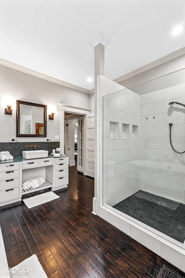 full bathroom featuring crown molding, hardwood / wood-style flooring, vanity, recessed lighting, and tiled shower