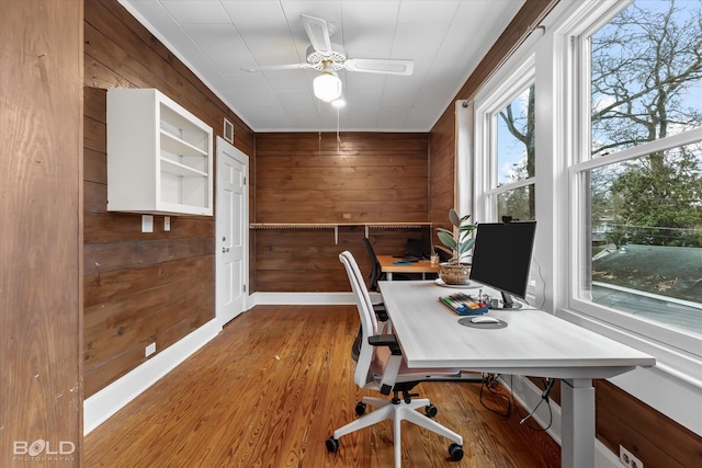 office space with ceiling fan, wood walls, wood finished floors, and visible vents