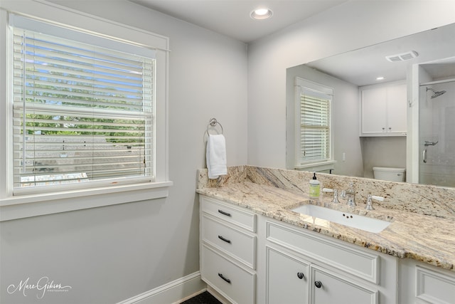 bathroom with visible vents, vanity, baseboards, toilet, and tiled shower