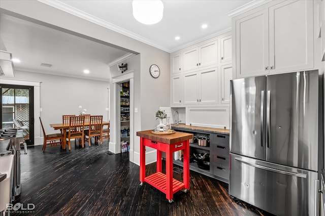 kitchen with dark wood finished floors, baseboards, white cabinets, freestanding refrigerator, and ornamental molding