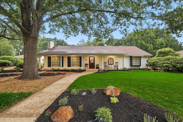 ranch-style home with a porch, brick siding, a front yard, and a chimney