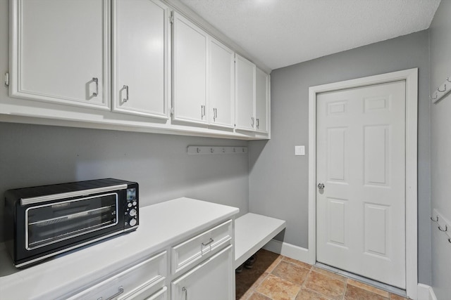 mudroom featuring baseboards, stone finish flooring, and a toaster